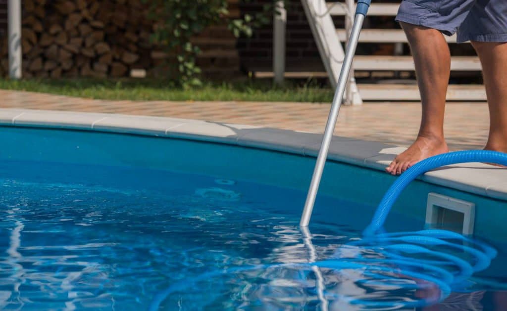 Photographie d'une homme nettoyant une piscine. Planète Eau Piscines, Construction, Rénovation, Entretien. Artisan pisciniste sur Aix en Provence et ses alentours.